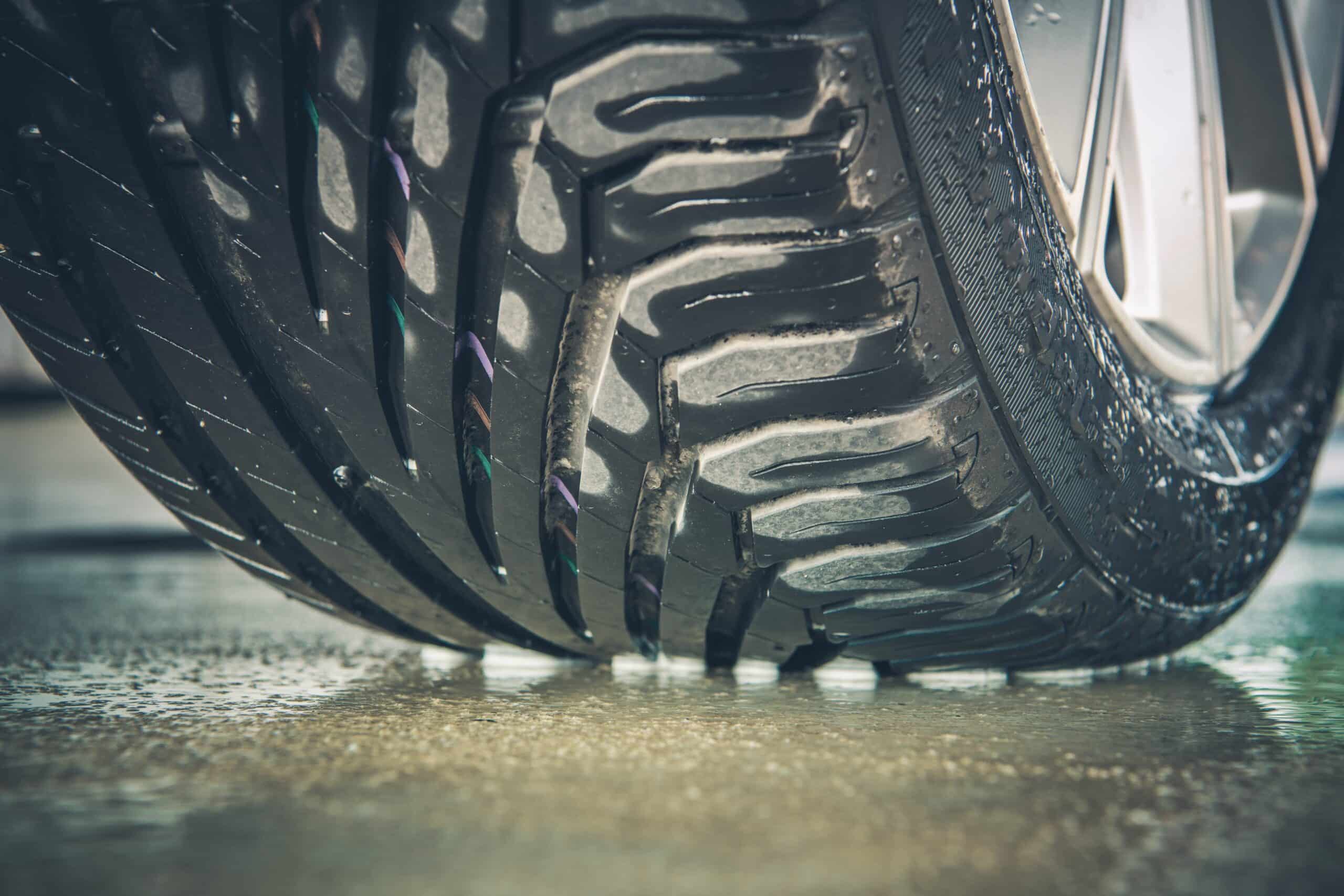 Close-up of a car tire tread on wet pavement