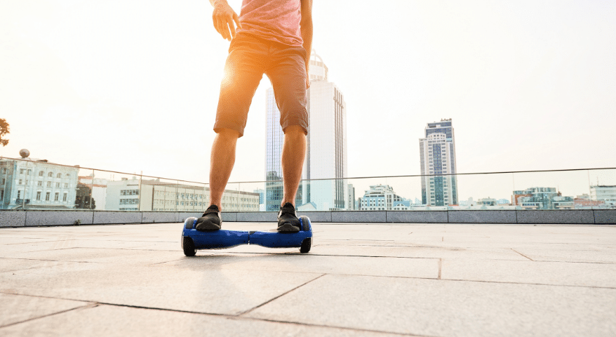 Person riding a hoverboard on pavement with a city skyline in the background