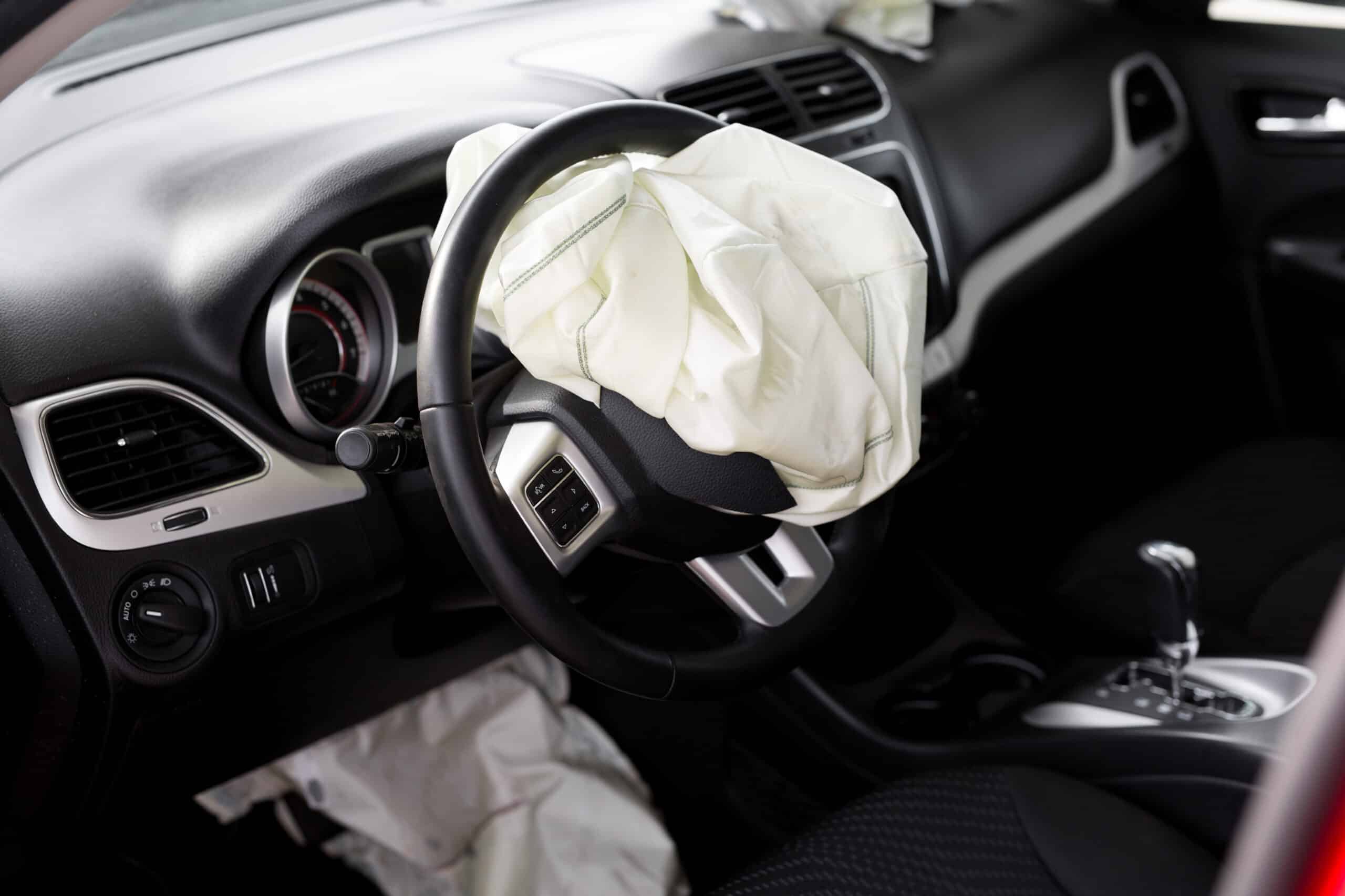Car interior with a deployed airbag on the steering wheel
