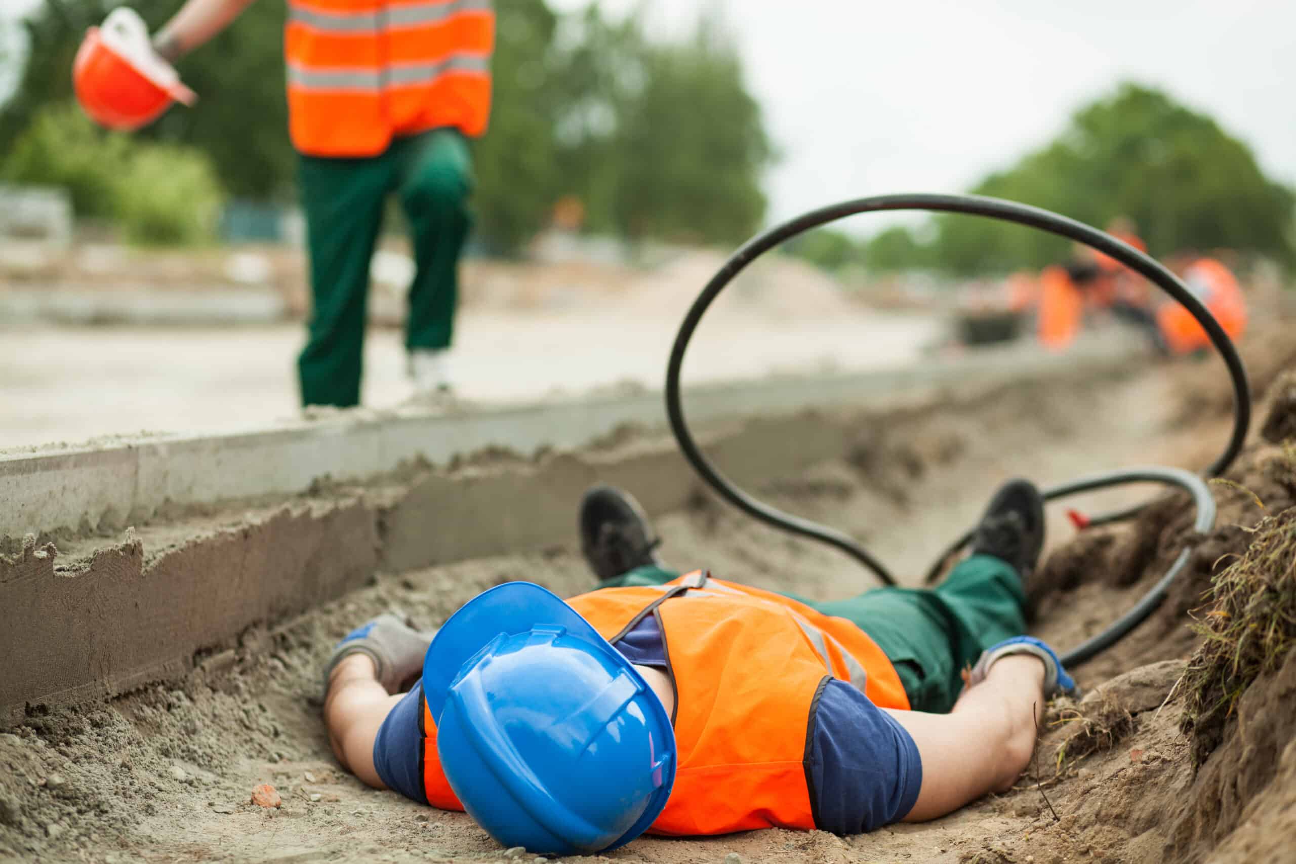 Construction worker lying injured on the ground beside an electrical cable as a coworker approaches