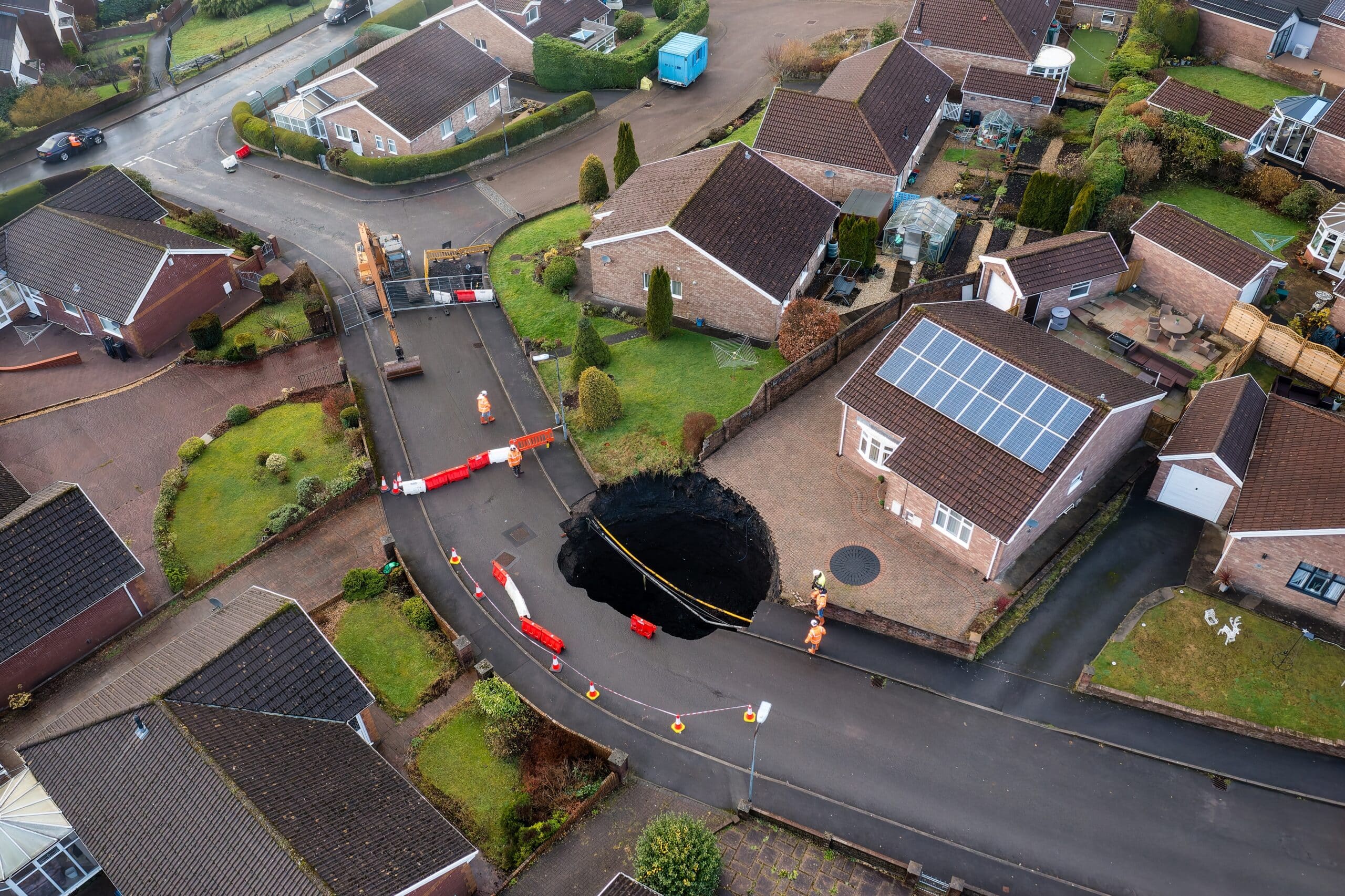 Aerial view of a sinkhole opening in a road in a residential neighborhood
