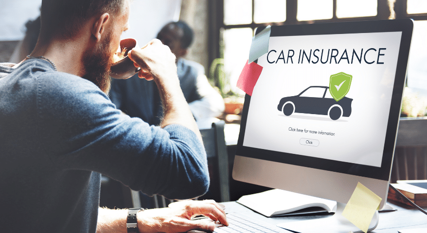 Man on the phone at a desk viewing a Car Insurance website