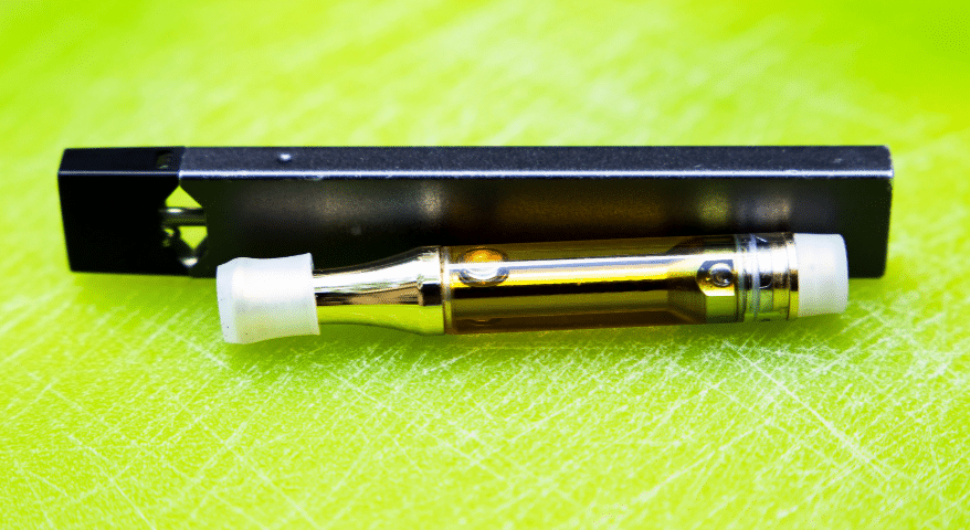 Vape pen device resting on a green surface