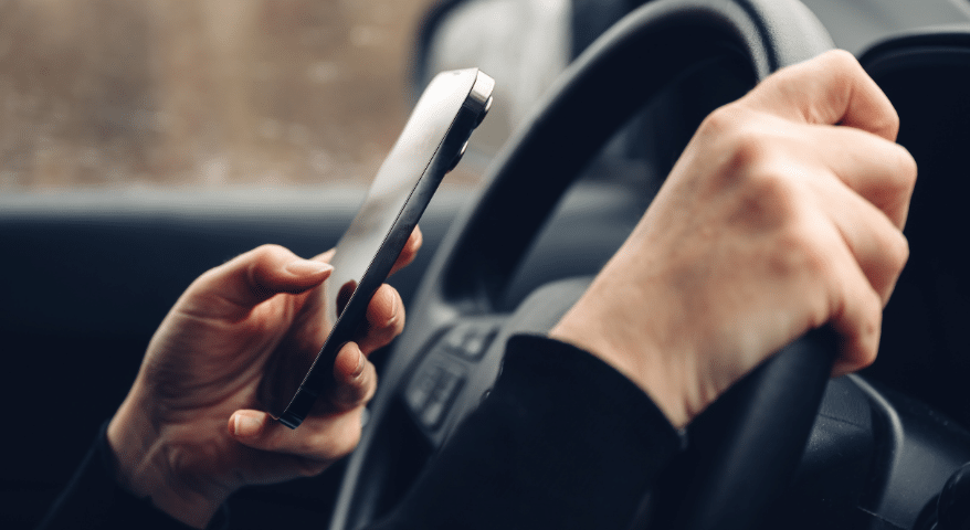 Hand holding a phone while driving with the other hand on the wheel