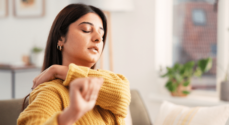 Woman at home holding her shoulder in discomfort