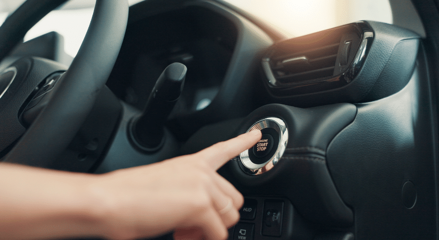 Finger pressing a keyless ignition start button in a car