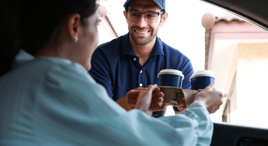 Delivery worker handing a coffee to a customer