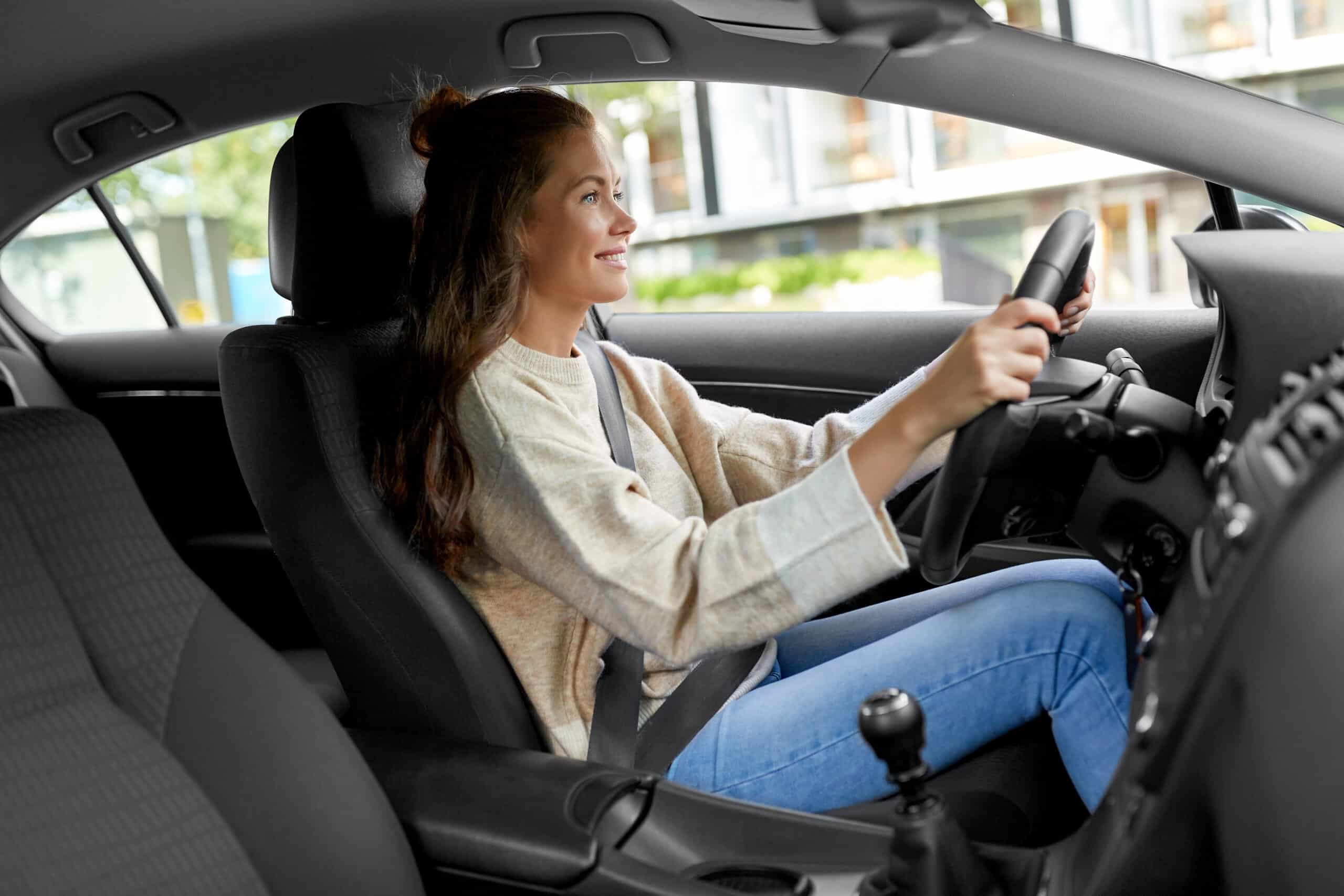Woman smiling in the driver's seat with her hands on the steering wheel