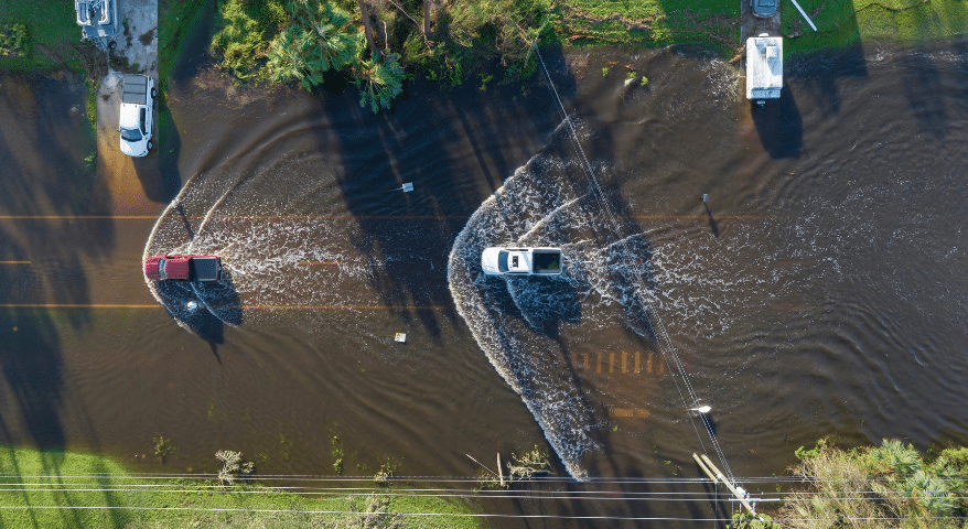 Aerial view of cars driving through a severely flooded road
