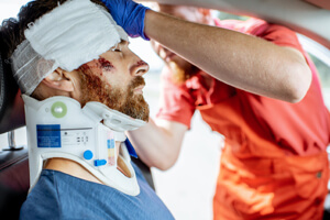 A man in a neck brace is treated by a doctor after a catastrophic injury.