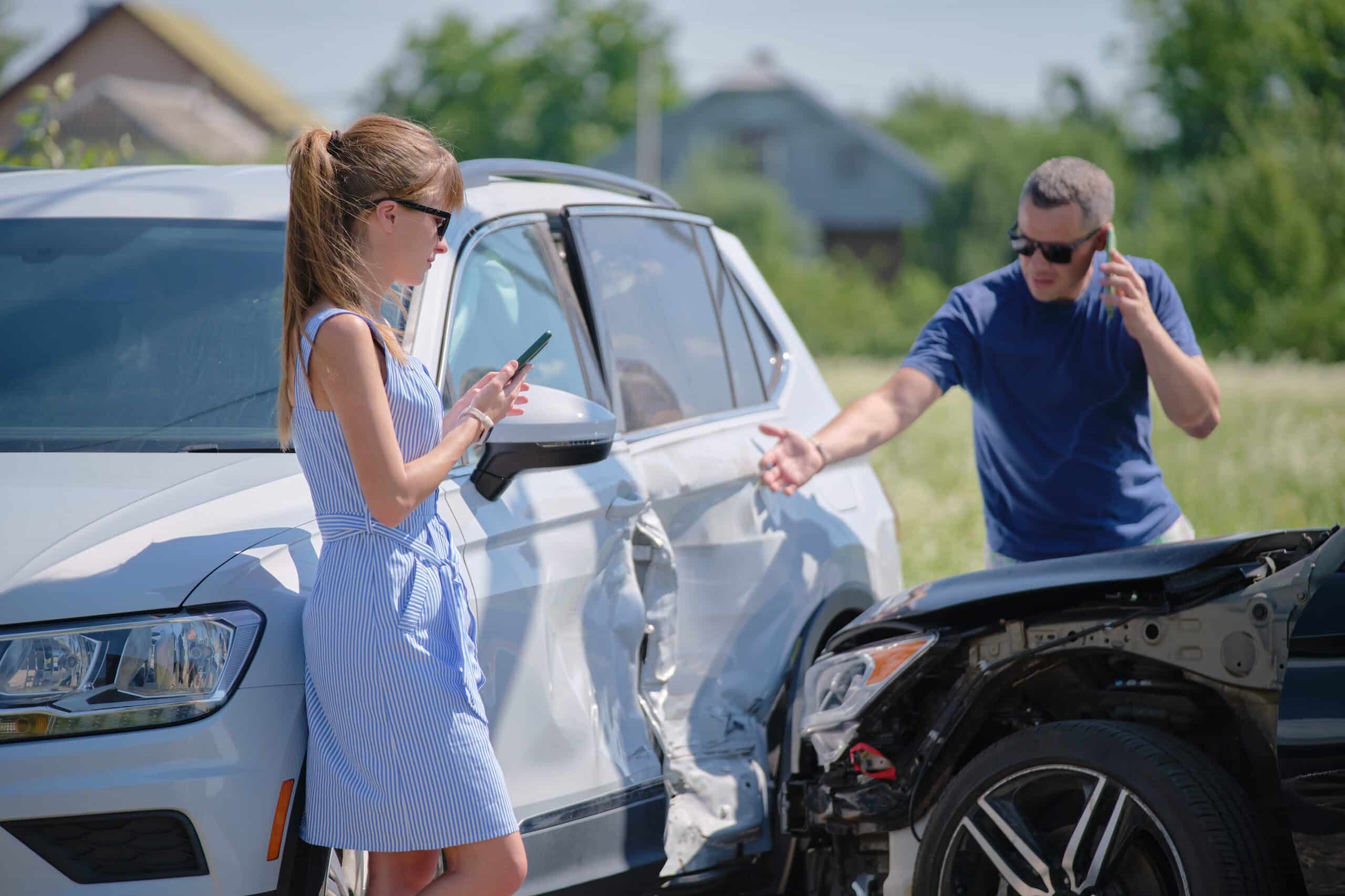 Woman and man exchanging information beside two cars after a collision