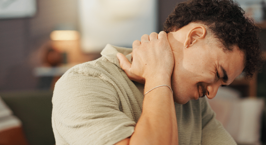 Man wincing in pain while holding his neck