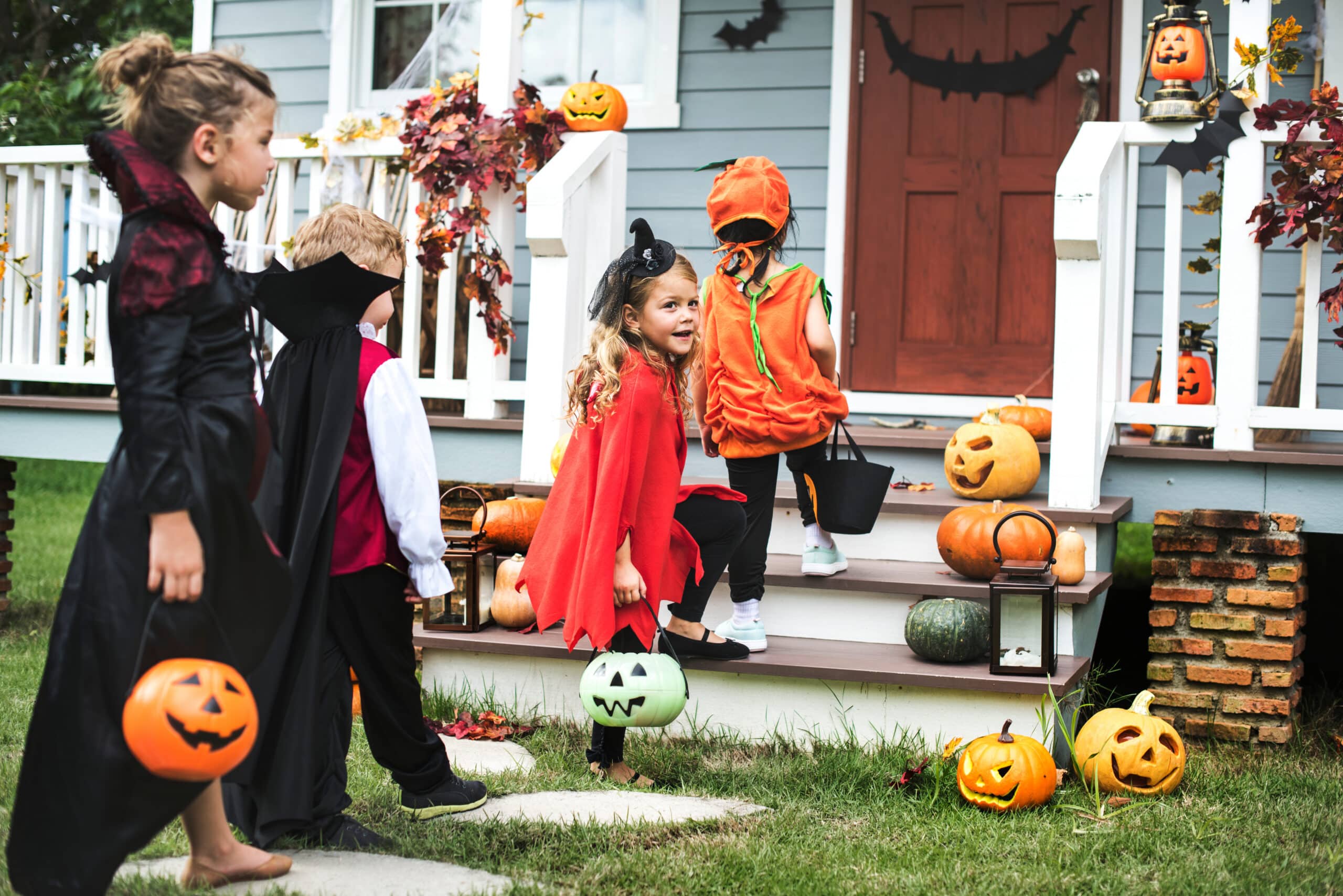 Children in Halloween costumes trick-or-treating on a decorated porch