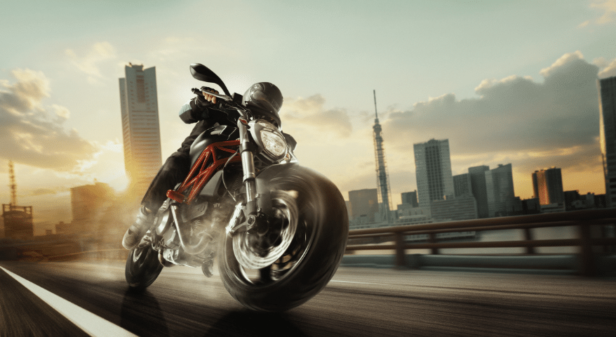 Motorcyclist riding fast with a city skyline in the background