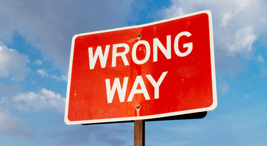 Red Wrong Way road sign against a blue sky