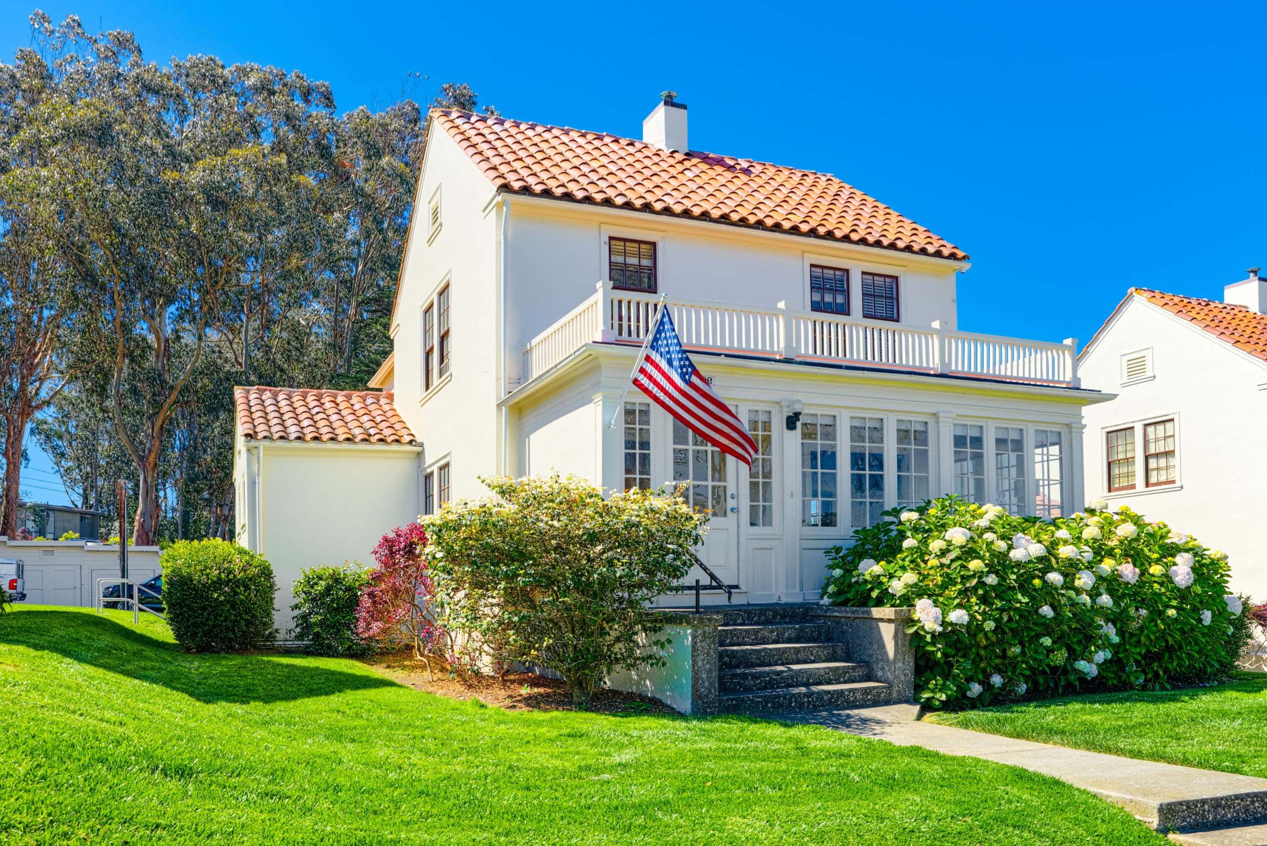 Two-story rental house with an American flag and landscaped front yard