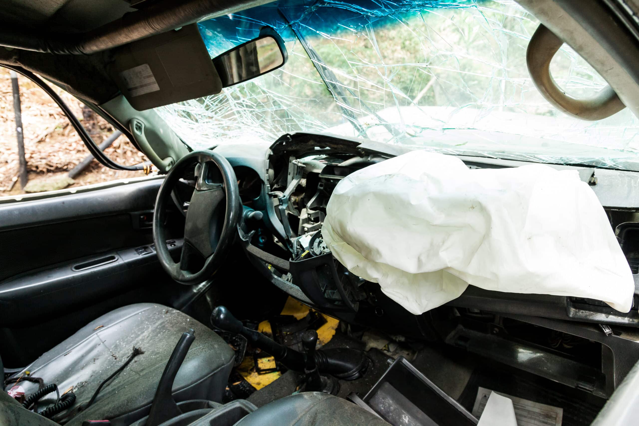 Interior of a wrecked car with a deployed airbag and shattered windshield