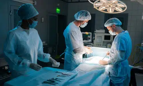 Three members of a medical team in a surgery room preparing for a patient’s procedure.