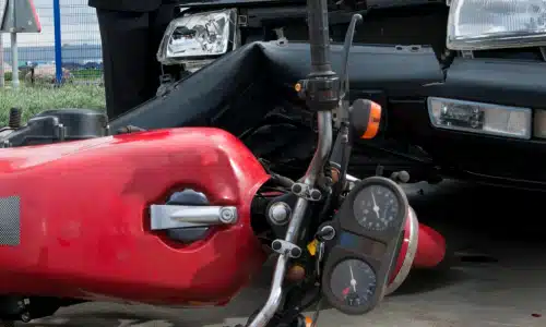 A large red motorcycle on its side after crashing headlong into a van.