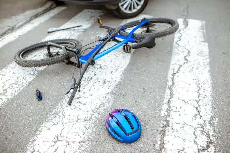Close-up of a damaged bicycle with visible scratches and dents, highlighting the aftermath of a bicycle accident on a city pavement.