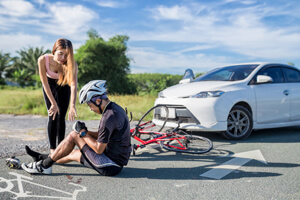 A person is hit by a car while they are riding on their bicycle. 
