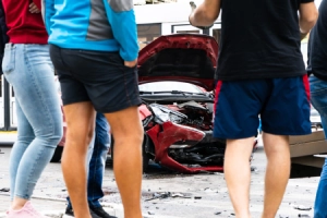A crowd gathering around the scene of a car accident on an urban road.