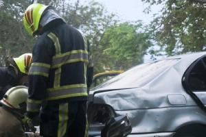 Firefighters responding to the scene of a car accident and attempting to open the vehicle.
