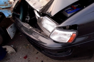 A closeup of the point of contact between a blue car and a black car after a road accident.