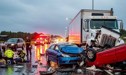 Aftermath scene of a multi-vehicle collision showing the damage truck and cars as the emergency responders assist injured victims