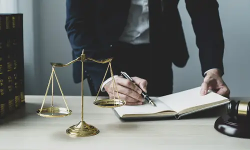 A Carrollwood bicycle accident lawyer leans over a table while writing on an open notebook placed on a work desk