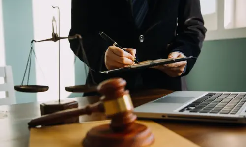 A catastrophic injury accident lawyer is writing on a file attached to a clipboard while standing in a Carrollwood law office