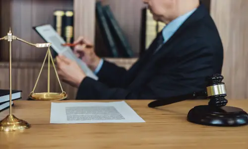 A motorcycle accident lawyer serving Carrollwood writes on a clipboard while sitting beside a table in the foreground