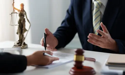 A product liability lawyer serving Carrollwood is gesturing with their hands while speaking to a client sitting at the other side of a desk