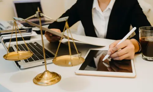 A Carrollwood spinal cord injury lawyer works on a tablet while holding a document in the other hand as she sits in her office.
