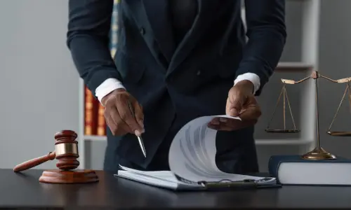 A Carrollwood stairway accident lawyer is flipping through pages of a document while standing behind his office desk