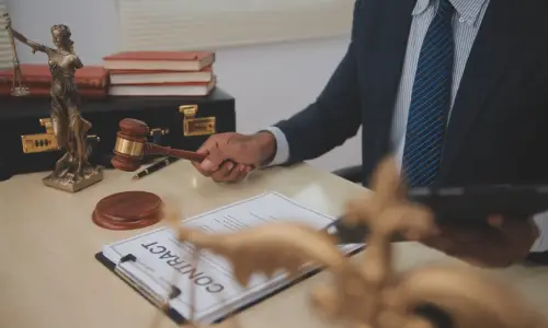 A Carrollwood swimming pool accident lawyer is reviewing a contract laid out on an office desk while holding a hammer in his right hand