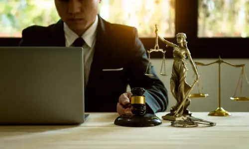 A Carrollwood truck accident lawyer using a laptop placed on an office desk while a figurine of "lady justice" is placed beside him