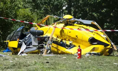 A helicopter that crashed during takeoff sits in a garden area, with a fire extinguisher positioned nearby.