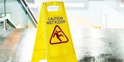 Yellow caution wet floor sign on a store floor near an entrance.