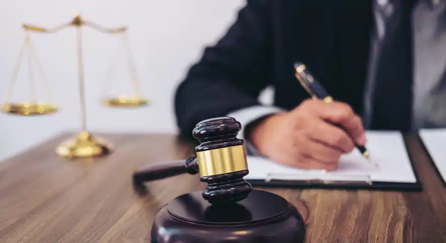 A Florida slip and fall lawyer sits ata a table with a hammer and gavel and balance scales while signing legal documents