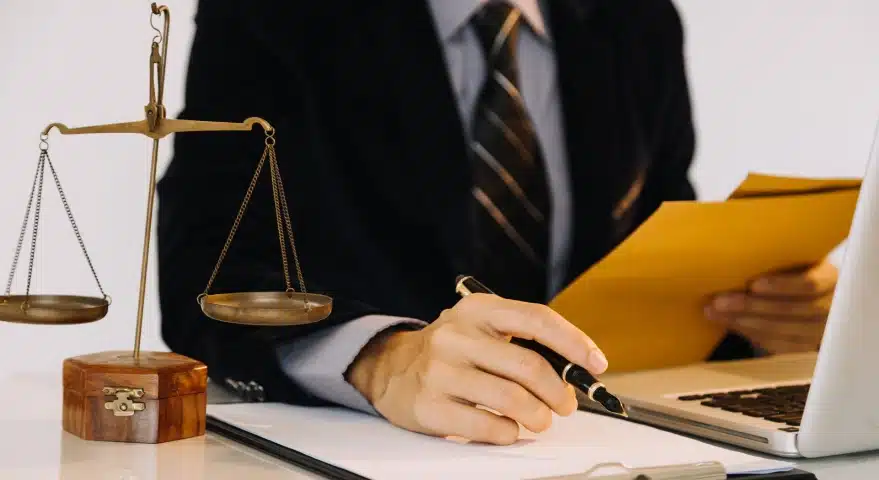 A Florida slip and fall lawyer works on a laptop while checking details on a document on the office desk