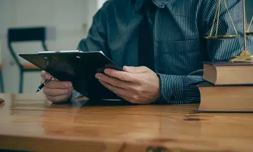 A Riverview construction accident lawyer reading a client's personal injury policy on a clipboard while seated at his desk.