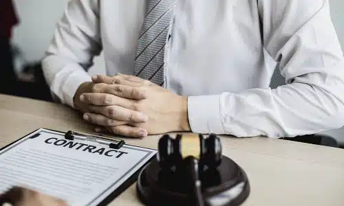 A Riverview medical malpractice lawyer presenting a client's insurance contract to them from behind a wooden desk in an office.