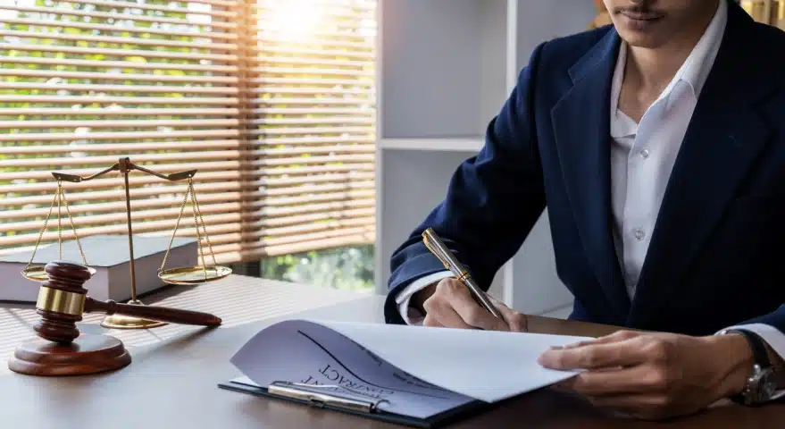A slip and fall lawyer serving Florida holds a document attached to a clipboard while signing the inner pages