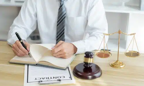 A Tampa workers compensation lawyer writing on a notebook placed on top of a contract while sitting in a law office