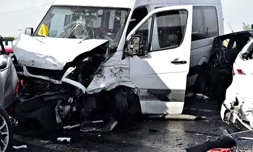 A truck accident in the middle of a highway involving a van and several other vehicles.