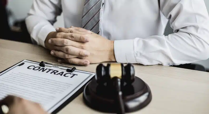 A fall injury lawyer sits at a table with a contract on top facing the opposite way