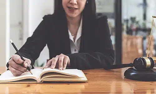 A manufacturing defect lawyer working on papers for a client at her desk in an office.