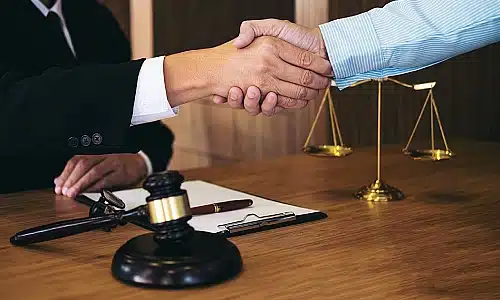 A personal injury lawyer shaking hands with a client in an office during a meeting.